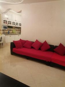 a red couch with red pillows in a living room at Villa luxueuse et chaleureuse in Saïdia