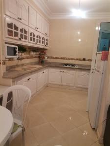 a kitchen with white cabinets and a white refrigerator at Villa luxueuse et chaleureuse in Saïdia