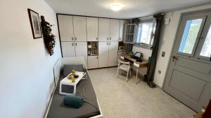 a kitchen with white cabinets and a table and a desk at Su Casa KEA in Korissia