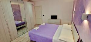 Cette petite chambre comprend un lit violet et un miroir. dans l'établissement La Casetta del Vicolo, à Narni