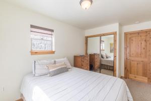 a bedroom with a large white bed and a mirror at Alpenglow Unit 6 in Ouray