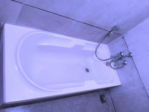 e bagno con vasca bianca e doccia. di Hotel Neptune Palace ad Ānand