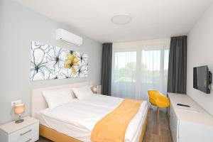 a bedroom with a bed and a desk and a window at Lelle Hotel in Balatonlelle