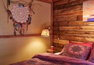 ein Schlafzimmer mit einer Holzwand, einem Bett und einer Lampe in der Unterkunft Chalet Mont Juru - Romantisch 2-persoons Chalet in Houffalize