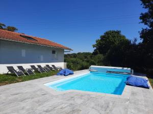 a swimming pool with chairs and a house at Bed & Breakfast L'Etape Basque in Bidart