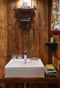 a bathroom with a white sink and a wooden wall at Tiny House Cetturu - 2-pers luxe en romantisch boshuisje in Houffalize