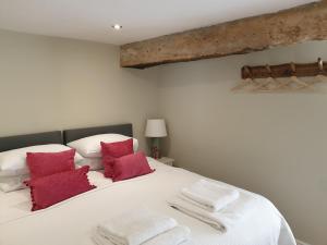 a bedroom with a large white bed with red pillows at Trouble House in Tetbury +29 photos