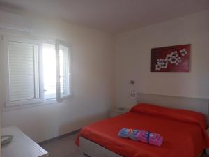 sypialnia z czerwonym łóżkiem i 2 oknami w obiekcie La casa di Isa w mieście Maracalagonis