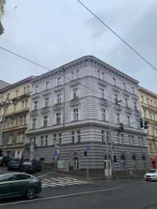 een groot wit gebouw in een stadsstraat met auto's bij Luxury Residence Kmochova in Praag