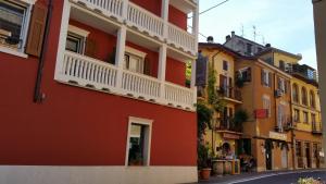 a red building with a white balcony on a street at Hotel Danieli La Castellana lago di Garda in Brenzone sul Garda