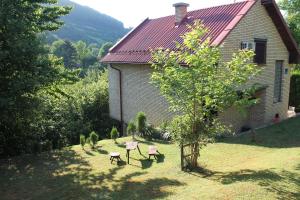 a house with a yard with two chairs and a tree at Holiday Home Zbilje in Visoko