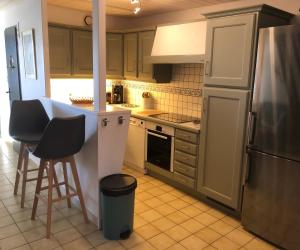 a kitchen with a refrigerator and a counter with stools at Le Phare - Gîte de mer Boyardville in Boyardville