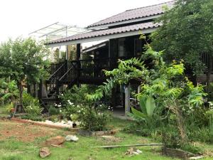 a house with a deck and plants in the yard at Bo Cabin in Garden โบคาบิน อิน การ์เดน in Ban Nong Ki