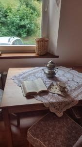 a table with an open book and a tea set at Chopina 6 na zielonym wzgórzu in Jedlina-Zdrój