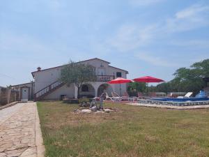 una casa con un patio con piscina y sombrillas en Apartments Chipo en Vodnjan