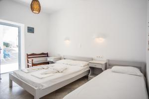 two beds in a room with white walls at Hotel Mantalena in Antiparos Town