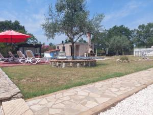 a yard with a fire pit and an umbrella at Apartments Chipo in Vodnjan