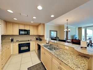a large kitchen with wooden cabinets and a sink at Portofino Island Resort #5-1403 in Pensacola Beach +32 photos