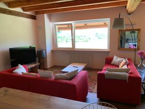 sala de estar con 2 sofás rojos y TV en AGRITURISMO MODOLO Belluno Dolomiti en Belluno