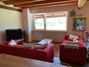 a living room with two red couches and a tv at AGRITURISMO MODOLO Belluno Dolomiti in Belluno