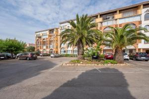 two palm trees in a parking lot in front of a building at Le Tusco in Cap d'Agde