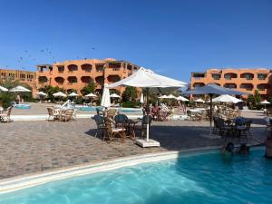 a swimming pool with chairs and tables and umbrellas at Dream Lagoon Resort & Aqua Park in Marsa Alam City