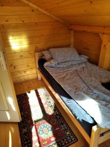 a bed in a wooden cabin with a rug at Brvnara koliba in Bor +12 photos