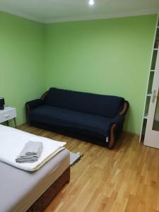 ein blaues Sofa in einem Zimmer mit Holzboden in der Unterkunft Apartman Radaković in Subotica