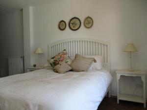 a bedroom with a white bed with two clocks on the wall at Casa Laibon in Gaucín