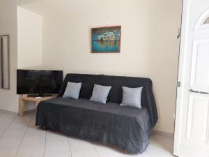 a couch with two pillows in a room with a tv at Casa Blanca (I) in Pyrgos Dirou