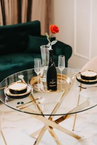 a glass table with glasses and a vase with a rose at Art Apartments Warszawska 21 Katowice in Katowice