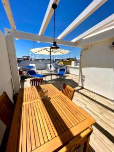 un tavolo in legno con sedie e un ombrellone su una terrazza di Apulia Holidays a Mola di Bari
