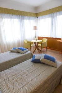 two beds in a hotel room with a table and chairs at Hotel Futura Centro Congressi in Naples