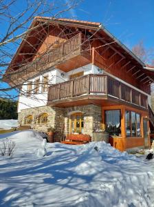 a large log house with a balcony in the snow at Pokoje v šumavském domě in Nové Hutě