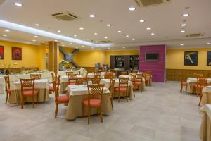 a restaurant with white tables and chairs and a purple wall at Hotel Futura Centro Congressi in Naples