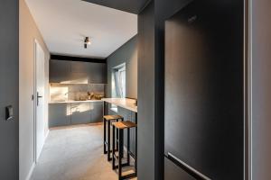 cocina con paredes negras y taburetes de madera en Loft House Apartment Studio z ogródkiem 3, en Rybnik