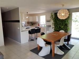 een keuken en eetkamer met een houten tafel en witte stoelen bij Villa forest home avec piscine dans les gorges du verdon en Provence in Quinson