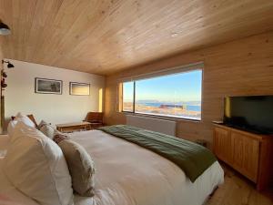 a bedroom with a large bed and a large window at Line Hotel Patagonia in Puerto Natales