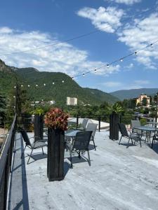 a patio with chairs and tables with mountains in the background at Borjomi Central in Borjomi