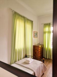 Schlafzimmer mit einem Bett und einem Fenster mit grünen Vorhängen in der Unterkunft Belfry House Nafplio in Nafplio