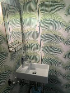 a bathroom with a sink and a leafy wallpaper at Beautiful big house with garden in Tübingen