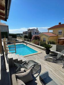 una piscina su una terrazza in legno con sedie di Histria apartment with own private pool near the beach a Banjole