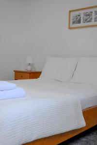 ein Bett mit weißer Bettwäsche und einem Bild an der Wand in der Unterkunft Belfry House Nafplio in Nafplio