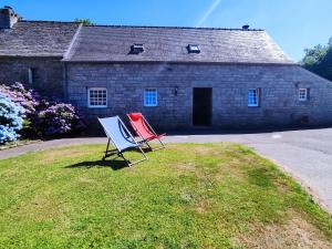two chairs sitting in front of a stone house at Les Gites de TY Dreux Monts d'arrée in Saint-Thégonnec