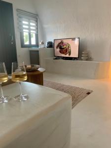 a living room with two wine glasses and a tv at White Curves Santorini in Akrotiri
