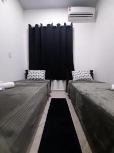 duas camas num quarto com uma cortina preta em Casa com piscina e churrasqueira em Cabo frio em Cabo Frio