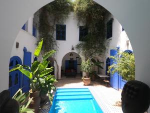 uma piscina em frente a um edifício com paredes azuis e brancas em Riad Chameleon em Marraquexe