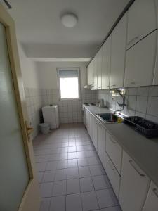 Elle comprend une petite cuisine avec des placards blancs et une fenêtre. dans l'établissement Katerina Apartment, à Ohrid