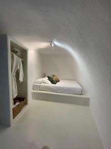 a small room with a bed in a white room at White Curves Santorini in Akrotiri