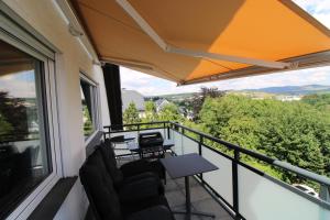 uma varanda com cadeiras, uma mesa e um guarda-sol em Maisonette-Wohnung Oststraße 37 em Schmallenberg